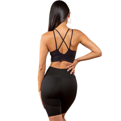 Back view of a model wearing a black peekaboo sports bra with elegant cross back design and high-waisted shorts.