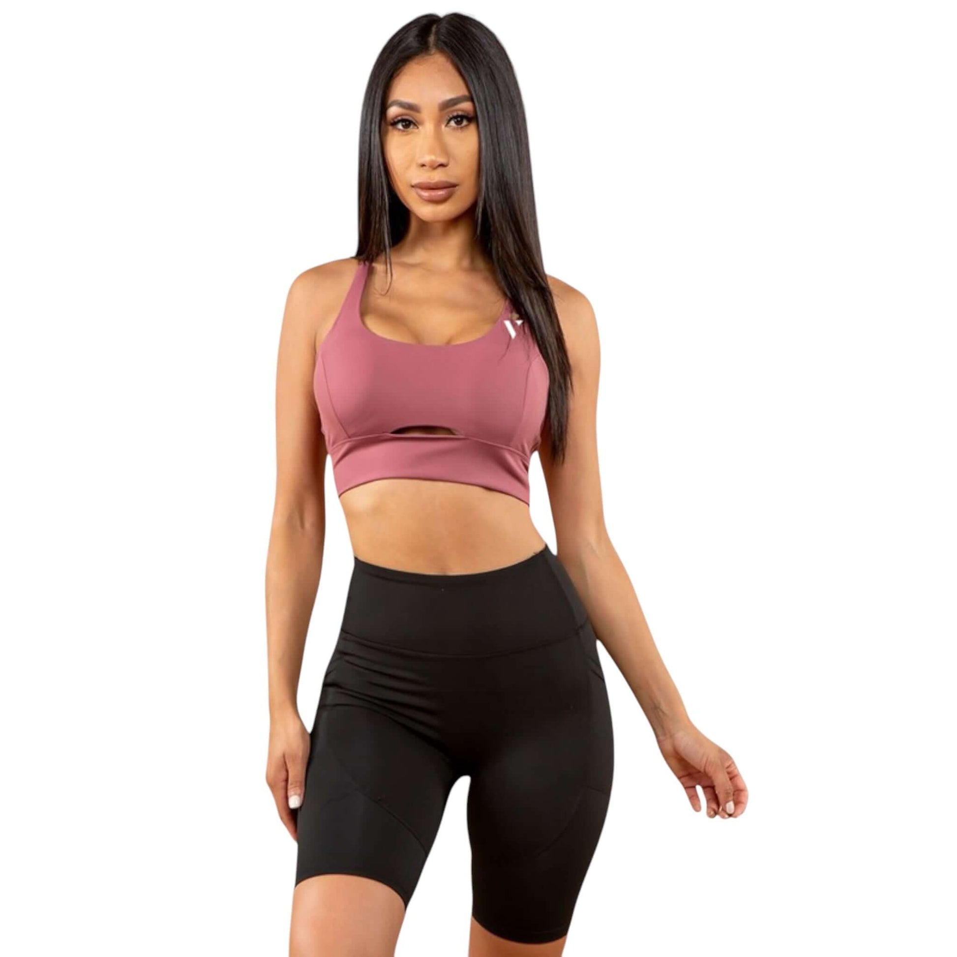 Model wearing a pink peekaboo sports bra paired with black shorts, showcasing activewear sportswear style.